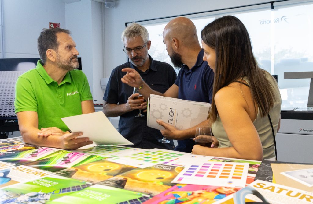 Especialista de Fujifilm y visitantes revisando muestras impresas y cartas de color sobre la mesa